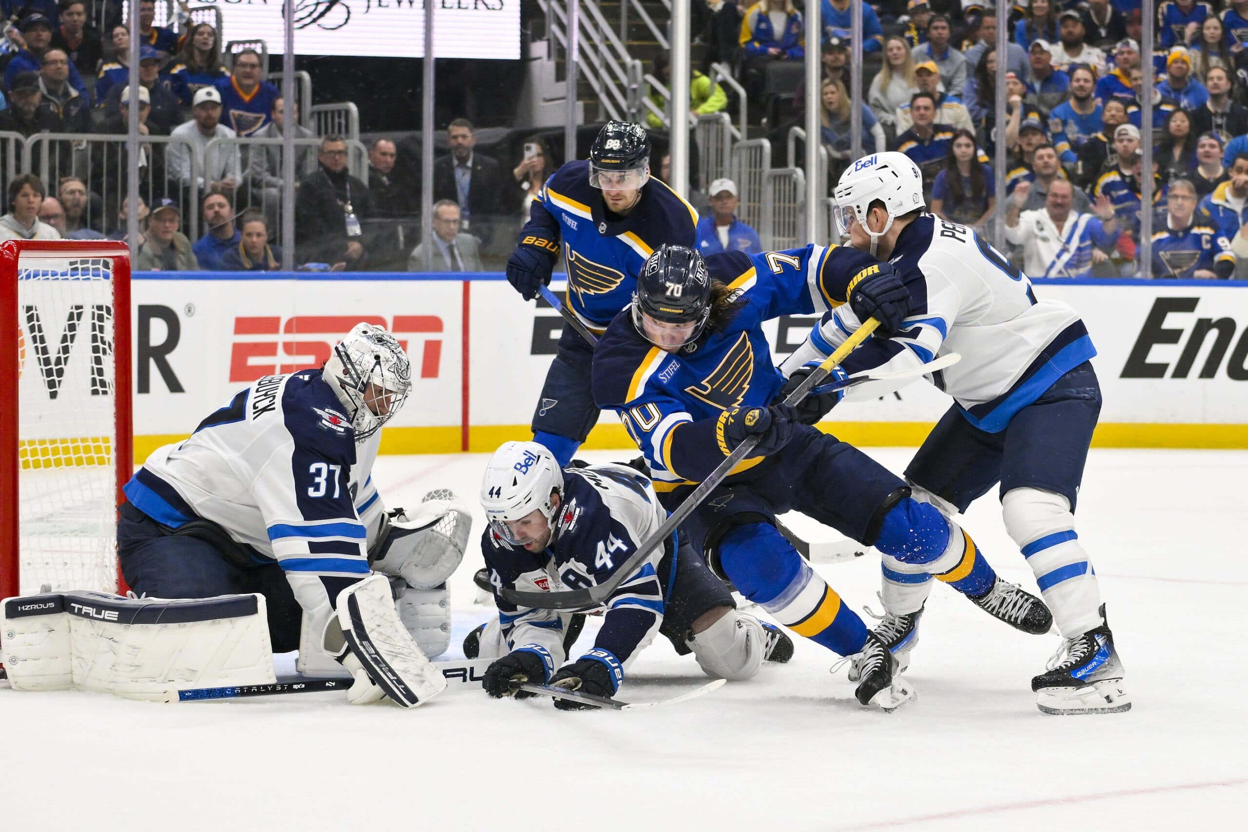 Winnipeg Jets goaltender Connor Hellebuyck (37) defenseman Josh Morrissey (44) and center Cole Perfetti (91) defend the net against St. Louis Blues center Oskar Sundqvist (70) during the second period in game three of the first round of the 2025 Stanley Cup Playoffs at Enterprise Center.